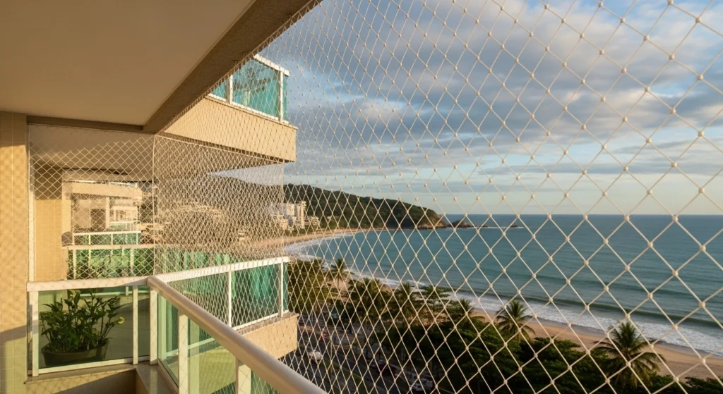 Rede de proteção cristal instalada em varanda de apartamento de frente para a orla da Praia Grande (Canto do Forte), mostrando resistência à maresia.