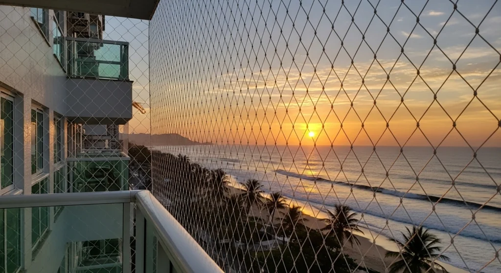 Rede de proteção cristal instalada em varanda de apartamento de frente para a orla de São Vicente, mostrando resistência à maresia.