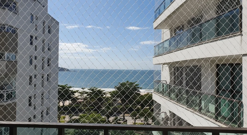 Rede de proteção cristal instalada em varanda gourmet no Guarujá (Pitangueiras), com ganchos de aço inox.
